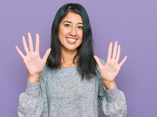 Beautiful asian young woman wearing casual clothes showing and pointing up with fingers number ten while smiling confident and happy.