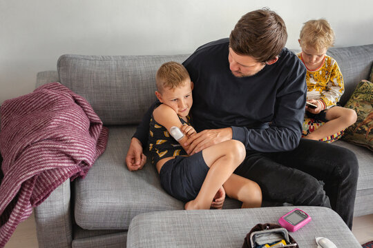 Father checking sons insulin pump, Sweden