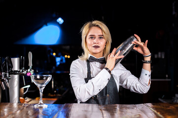 Girl bartender creates a cocktail on the saloon