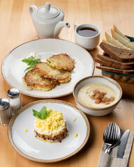 Typical russian lunch in a cafe: mushroom cream soup, mimosa salad and hot serving on a wooden table