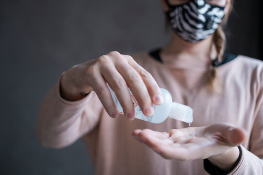 Woman with face mask using hand sanitizer, Sweden