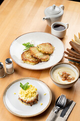 Restaurant set meal: potato fritters, mushroom cream soup and salad on a wooden table