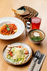 Business lunch in a italian cafe: caesar salad, chicken soup and tomato penne pasta, menu photography