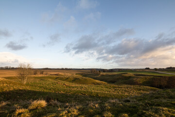 Obraz premium Landscape with rolling hills in the countryside. The morning sun lights a beautiful wide scene.