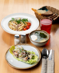 Italian cafe lunch: pasta, warm salad and vegetable soup, studio shot on a light wooden table