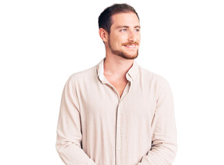 Young handsome caucasian man wearing casual clothes looking away to side with smile on face, natural expression. laughing confident.