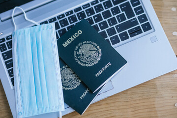 Pasaportes mexicanos y cubrebocas sobre un teclado de una computadora portátil