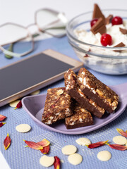 Granola bar. Healthy sweet dessert snack and breakfast. Cereal granola bar with nuts, chocolate, fruit and berries and coffe on a light blue background