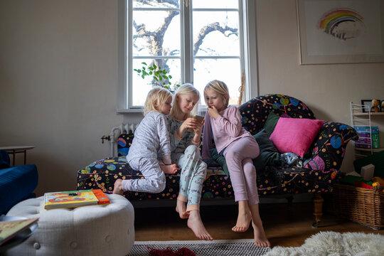 Sisters sitting on sofa, Sweden