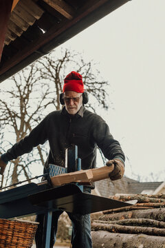 Senior man sawing wood, Sweden