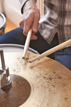 Close up on man holding drumsticks drumming on cymbal