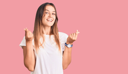 Beautiful caucasian woman wearing casual white tshirt doing money gesture with hands, asking for...