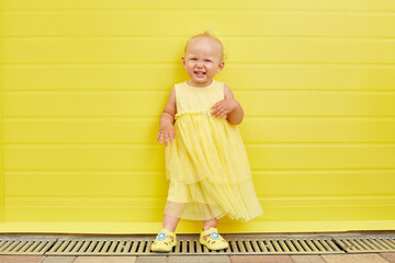 Adorable Little girl smiling on yellow background.