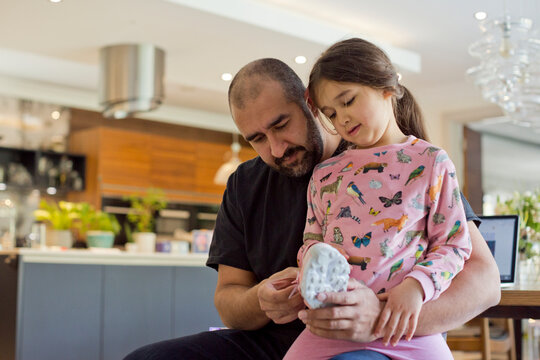 Father helping daughter to put shoes on, United Kingdom