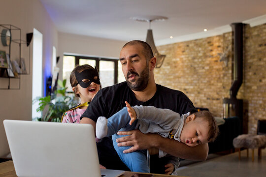 Man with children using laptop, United Kingdom