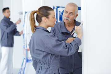 painters painting the wall while a senior man is supervising © auremar