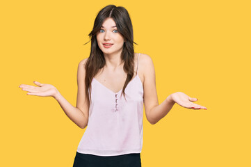 Young beautiful caucasian girl wearing casual clothes clueless and confused expression with arms...