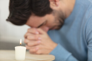 young man praying candle in the foreground