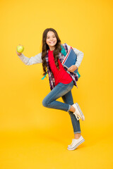 Fototapeta na wymiar Happy energetic kid run to school holding books and apple natural vitamin yellow background, energy