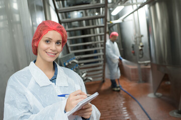 female factory supervisor wearing hairnet and taking notes