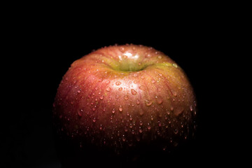 Red apple covered in water drops on black background. Health Concept with refreshing fruit.
