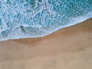 Fototapeta na wymiar Beach shore green water waves top view aerial drone shot