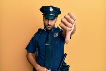 Handsome hispanic man wearing police uniform looking unhappy and angry showing rejection and...