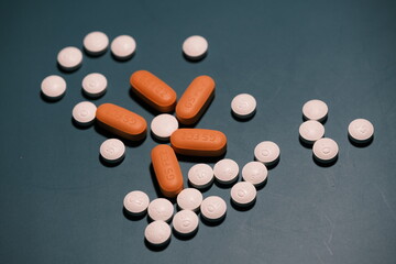 white and orange antiretroviral therapy pills for the treatment of HIV on tidewater green background.  World AIDS Day concept. Healthcare and medicine. Tablets and medication.