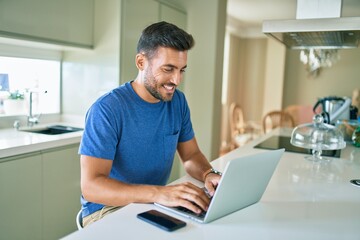 Young handsome man smiling happy working using laptop at home