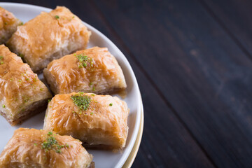 Turkish baklava in white plate with glass of tea in New year setting or decoration on dark wooden background