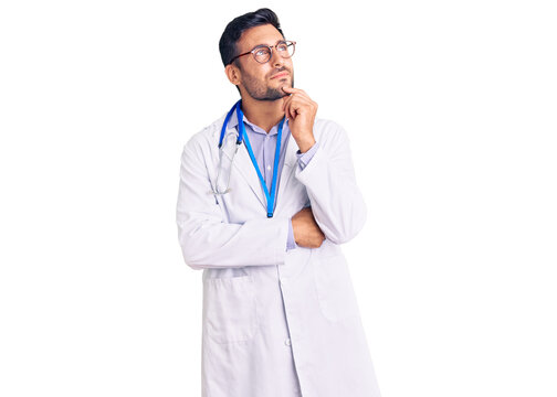 Young hispanic man wearing doctor uniform and stethoscope with hand on chin thinking about question, pensive expression. smiling and thoughtful face. doubt concept.
