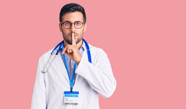 Young hispanic man wearing doctor uniform and stethoscope asking to be quiet with finger on lips. silence and secret concept.