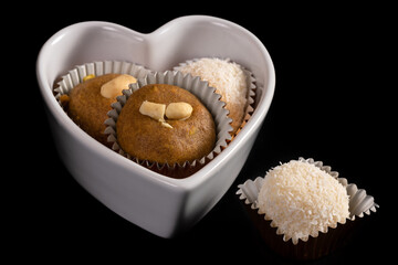 Indian homemade cookies in a heart shaped bowl isolated on black.