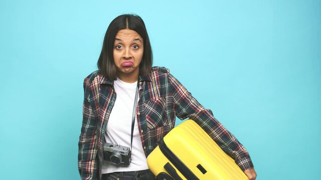 Young latin woman going to travel around the world  shrugs shoulders and open eyes confused