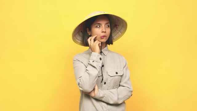 Young latin woman with vietnamite hat  confused, feels doubtful and unsure