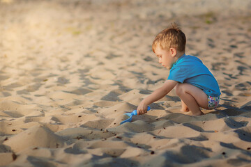 Boy playing on beach. Child play at sea on summer family vacation. Sand and water toys, sun protection for young child. Little boy digging sand, building castle at ocean shore.