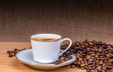 Espresso cup with coffee beans around on a hessian background 