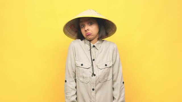 Young latin woman with vietnamite hat  shrugs shoulders and open eyes confused