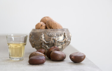 Walnuts, chestnuts and a golden liquor glass on a concrete surface