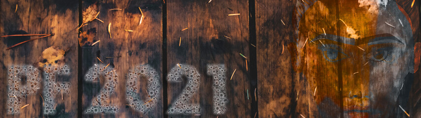 Happy new year 2021 card design. Happy new year 2021. Glowing font on an blue wood background with faces. Coronavirus themed font. Holiday glowing illustration. Covid 19 happy new year theme. PF 2021.