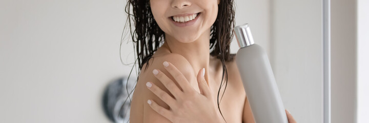 Close up cropped shot of happy positive young lady with shiny smile showering in modern bathroom...