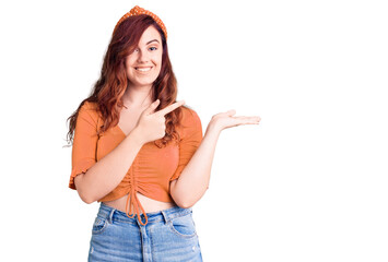 Young beautiful woman wearing casual clothes amazed and smiling to the camera while presenting with hand and pointing with finger.