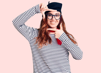 Young beautiful woman wearing french look with beret smiling making frame with hands and fingers with happy face. creativity and photography concept.