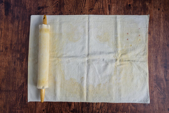 Preparation for baking, well used pastry cloth and covered wooden rolling pin on a wood table
