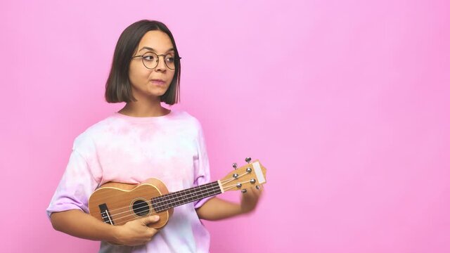 Young latin woman playing ukelele is saying a secret hot braking news and looking aside