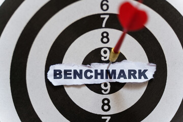 A piece of paper with the text is nailed to the target with a dart - BENCHMARK