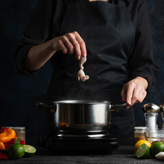 Close-up view of chef puts octopus into boiling water. Backstage of preparing delicious dinner with seafood on dark blur background. Frozen motion. Concept of exotic asian cuisine. Cooking process.