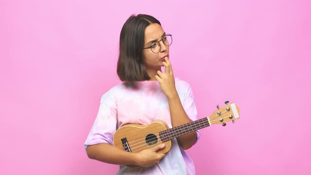 Young latin woman playing ukelele confused, feels doubtful and unsure