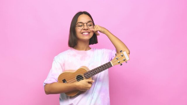 Young latin woman playing ukelele showing a mobile phone call gesture with fingers