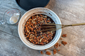 Whisking chocolate brownie batter ingredients with pecans flat lay